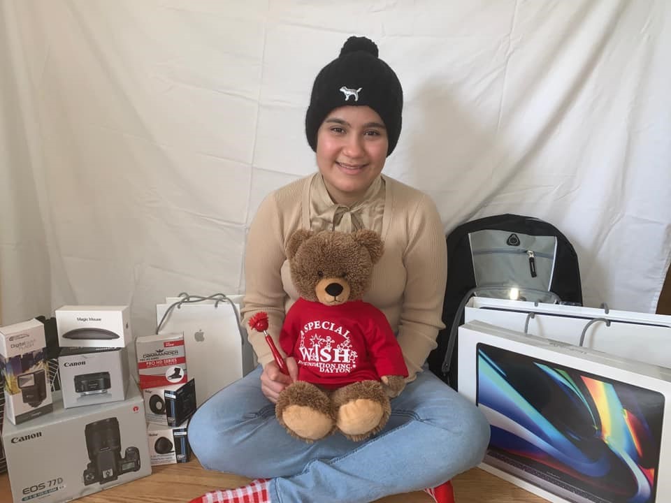 Young girl posing with stuffed bear and computer equipment 