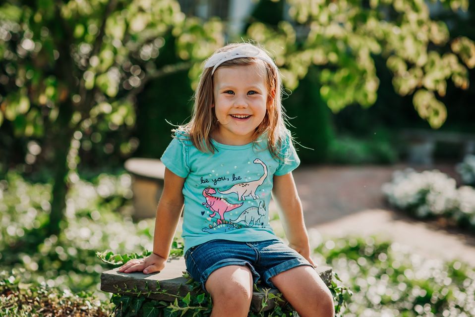 Young girl sitting outside on a bench posing for a photo